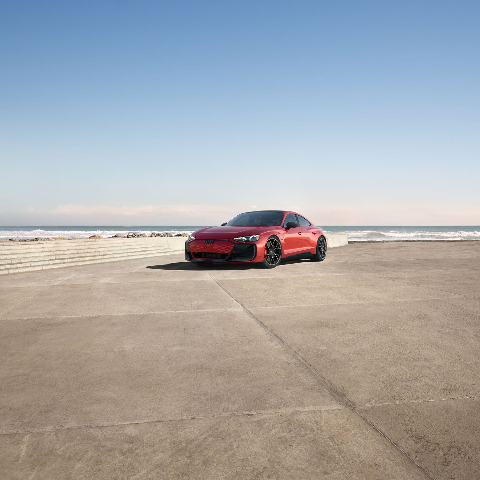 Une Audi RS e-tron GT rouge roulant sur une route côtière.