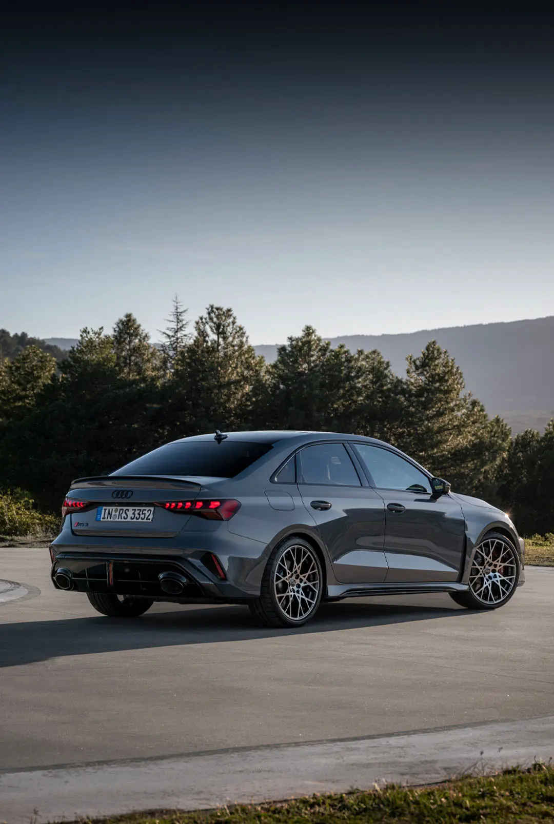 Vue de profil de l'Audi RS 3 gris devant un décor de montagne.