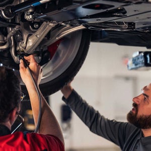 Service technician servicing a tire with another technician.