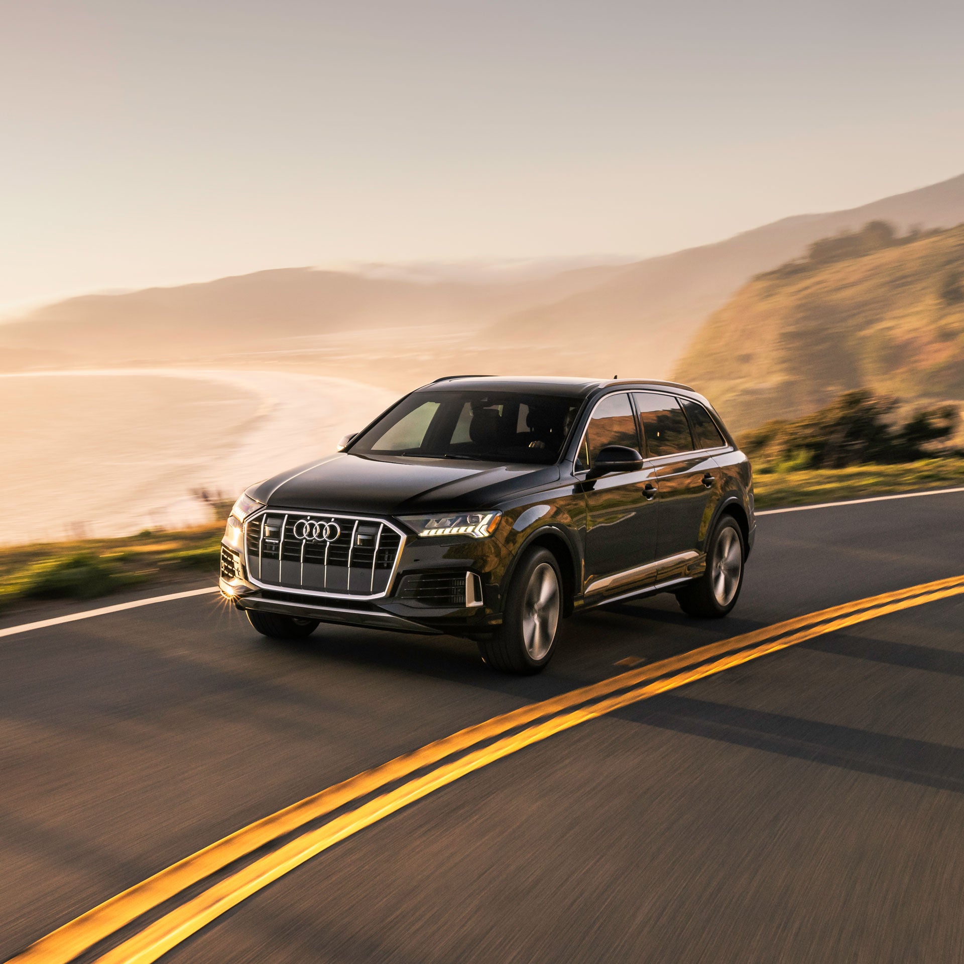 A black Audi Q7 accelerating up a mountain road. 