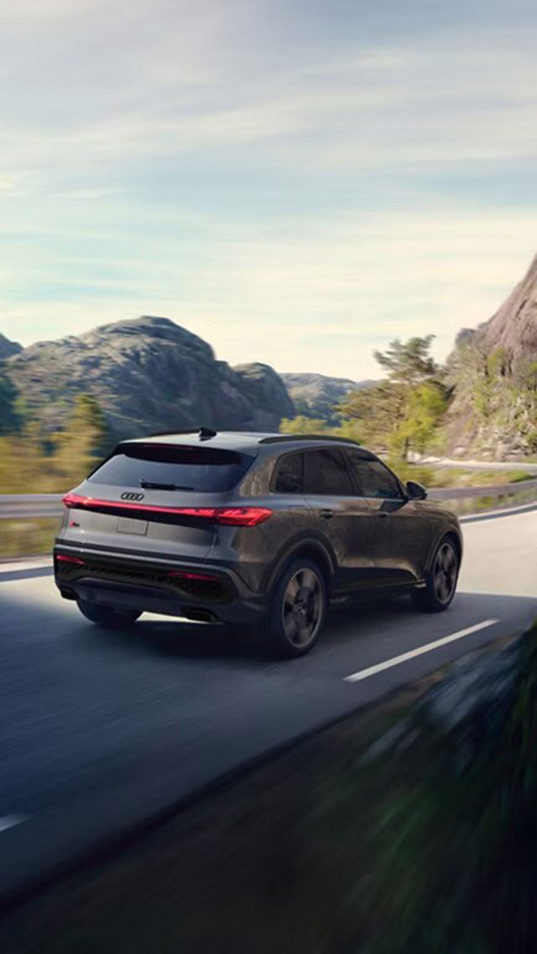 Three-quarter rear view of the 2025 Audi Q5 driving along a mountain road.