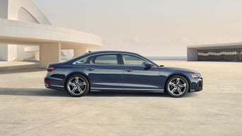 Side view of the Audi A8 parked by a modern building.