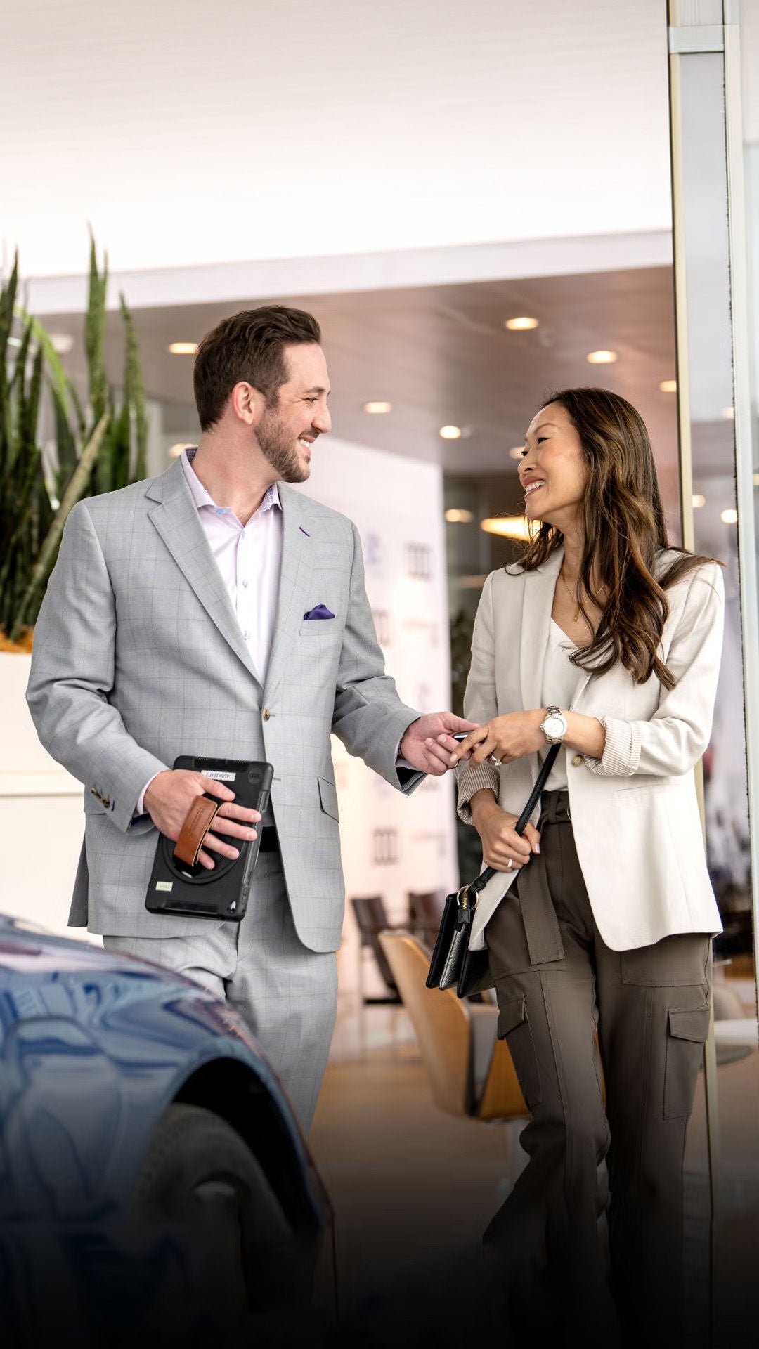 A smiling woman receiving the keys to her new Audi from the dealer.