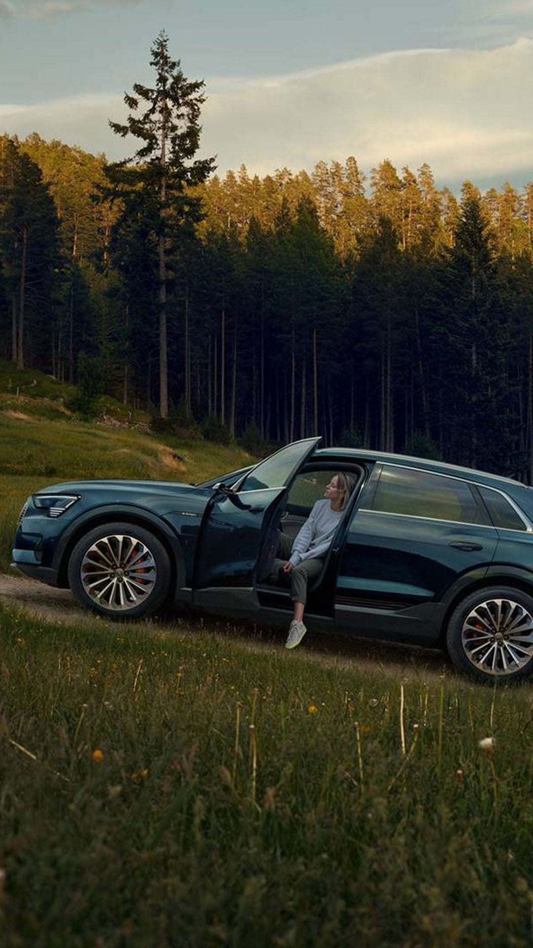 Une femme sortant de son Audi Q5 sur une route boisée.