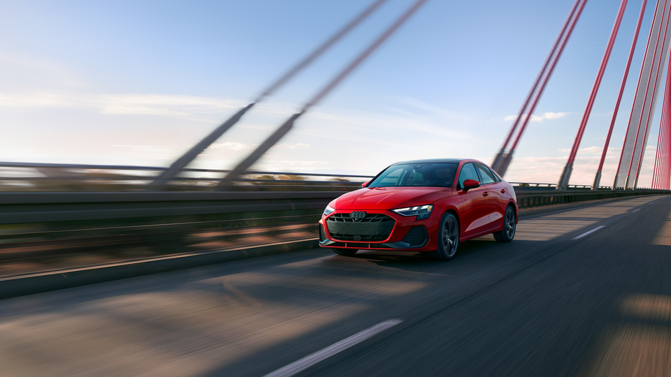 Red Audi A3 driving over a bridge. 