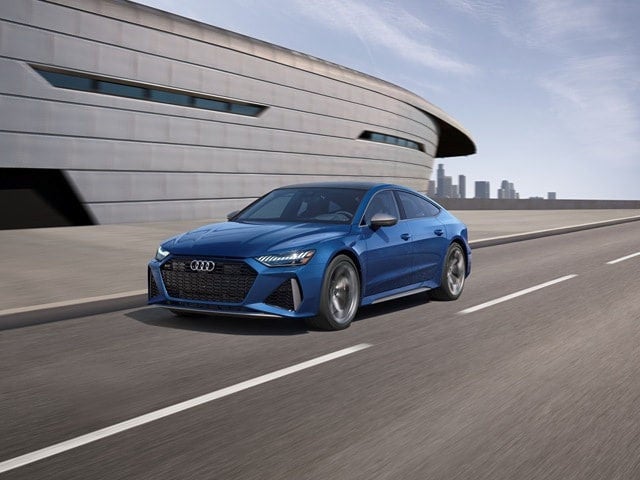 Audi RS7 side profile driving on road, showcasing performance sedan design