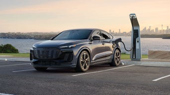 Vue de trois quarts avant de l'Audi Q6 Sportback e-tron stationnée et en charge.