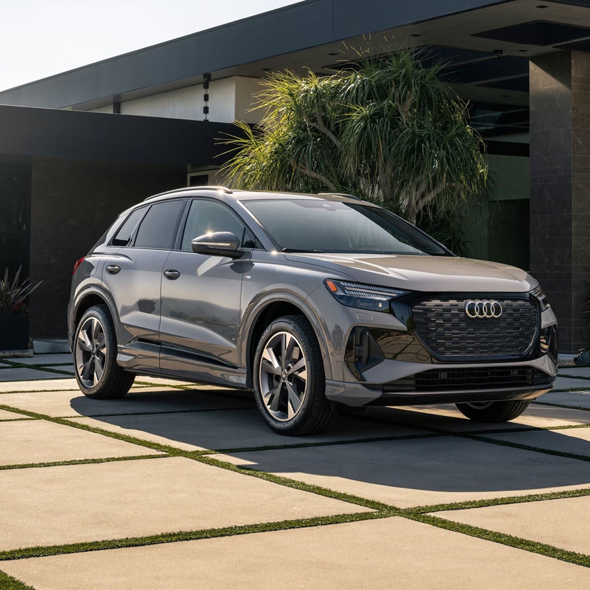 Three-quarter front view of the Audi Q4 e-tron parked in front of a modern home.