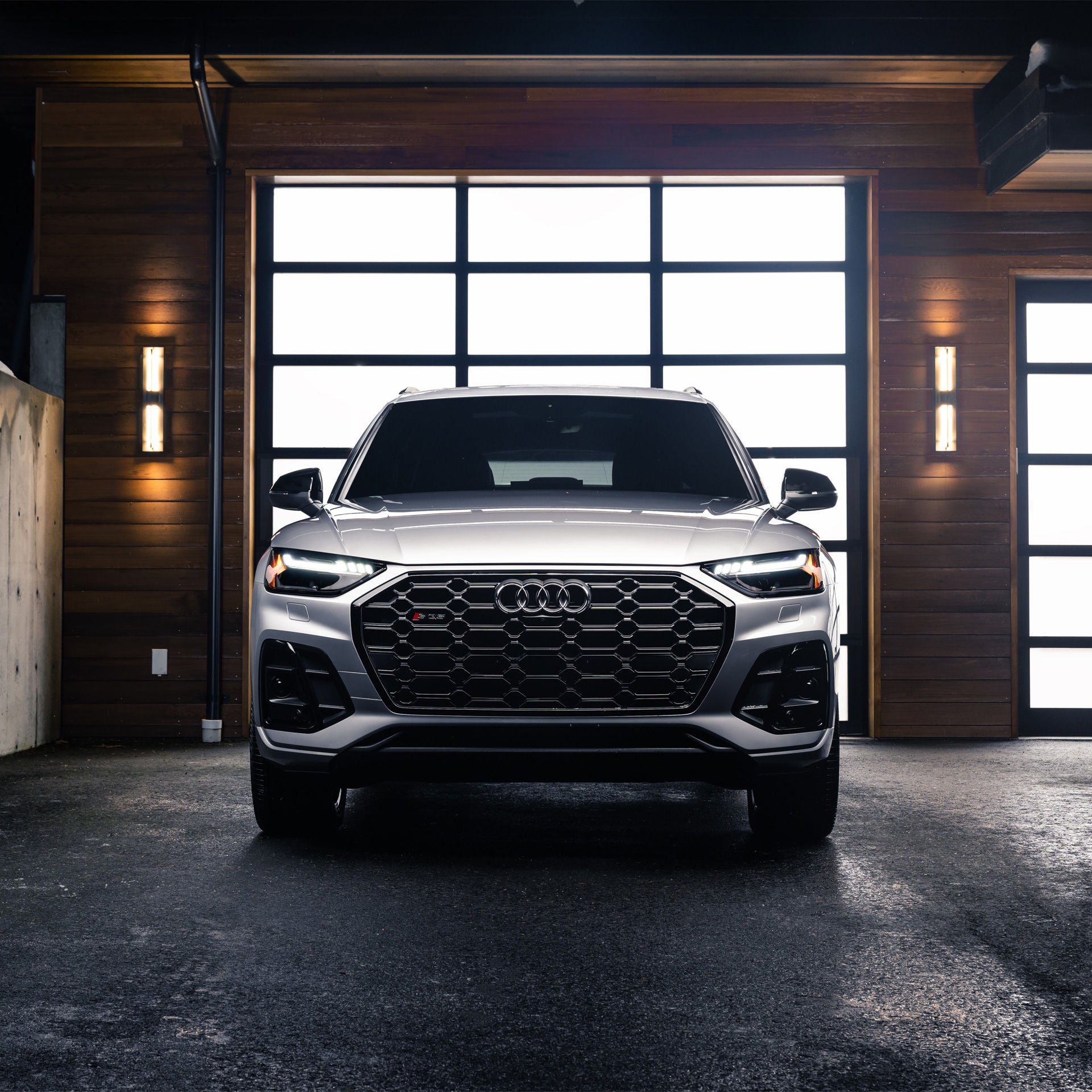 Front view of a silver Audi SQ5 parked in a wooden garage. 