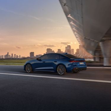 Aerial rear view of the Audi S5 accelerating on a city road.
