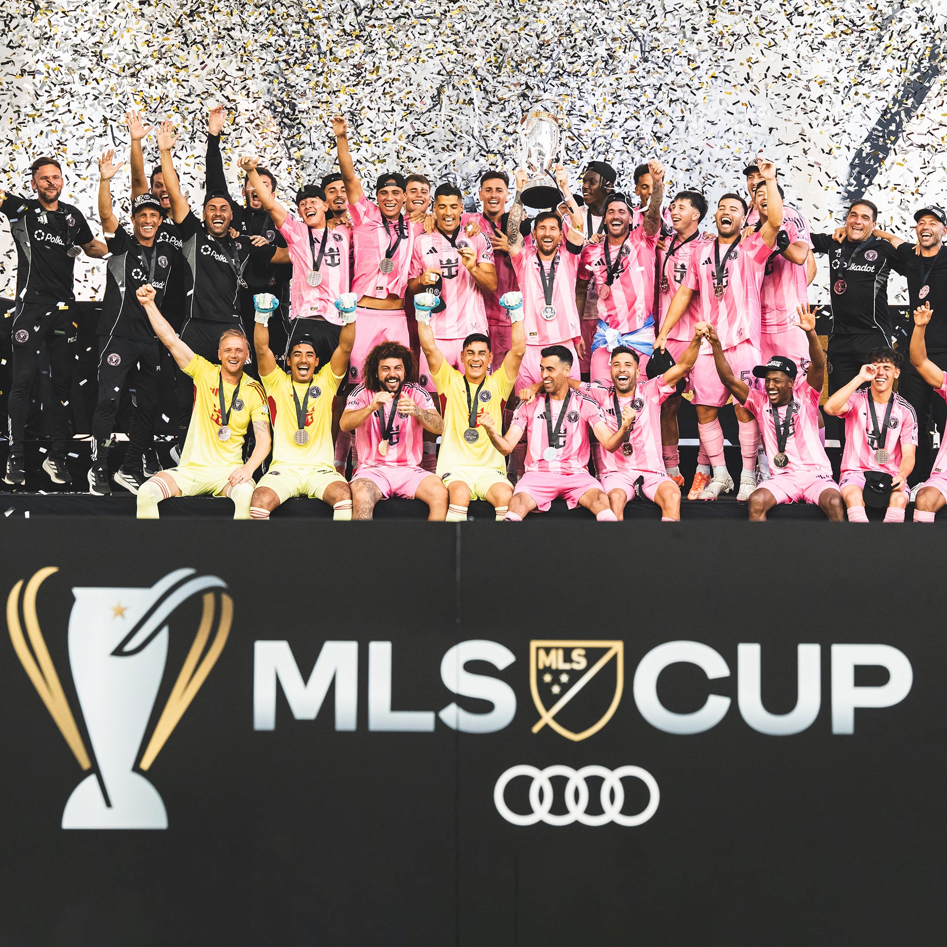 Soccer team taking a picture while celebrating win in stadium.