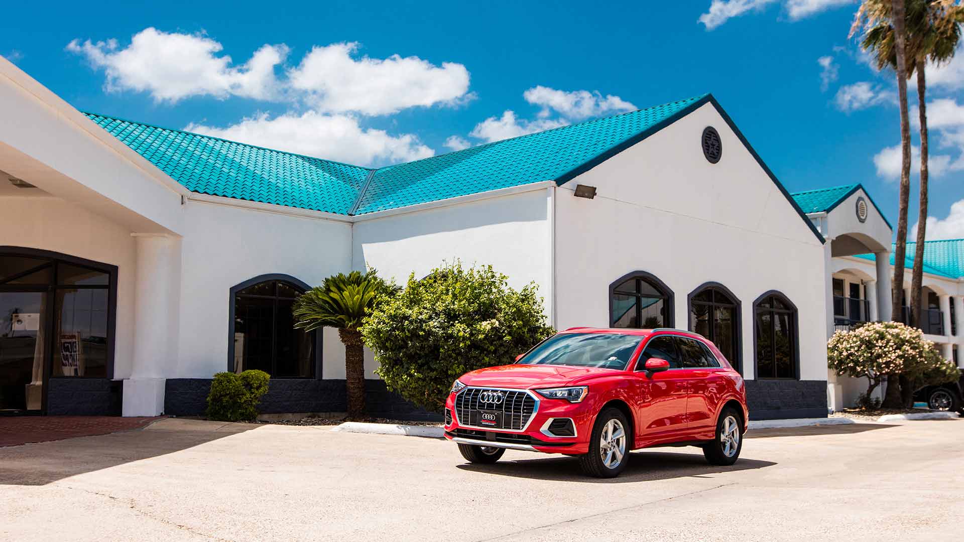 Side view of an Audi in front of a building with a blue roof