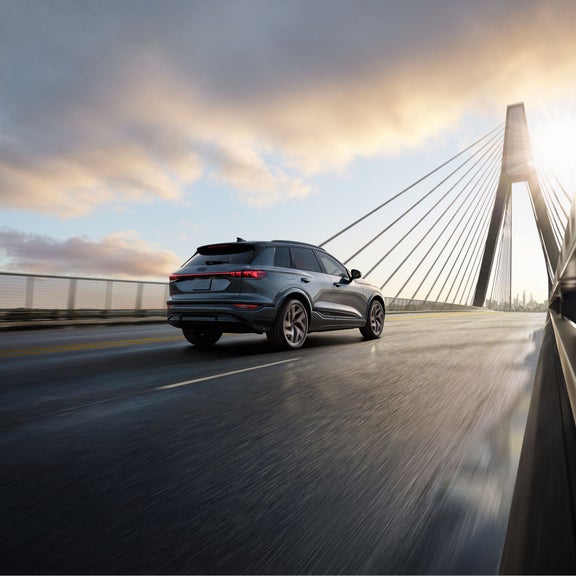 Three-quarter rear view of the Audi SQ6 e-tron accelerating on city bridge.