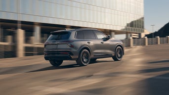 Three-quarter rear view of the Audi SQ7 accelerating on a city road.