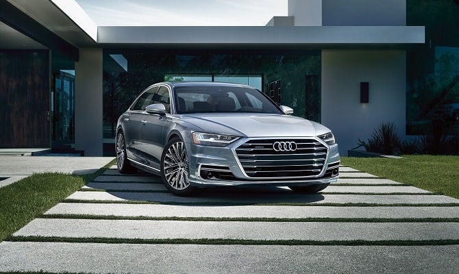 Audi A8 parked on walkway in front of house.