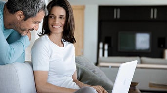Two people smiling over a laptop. 