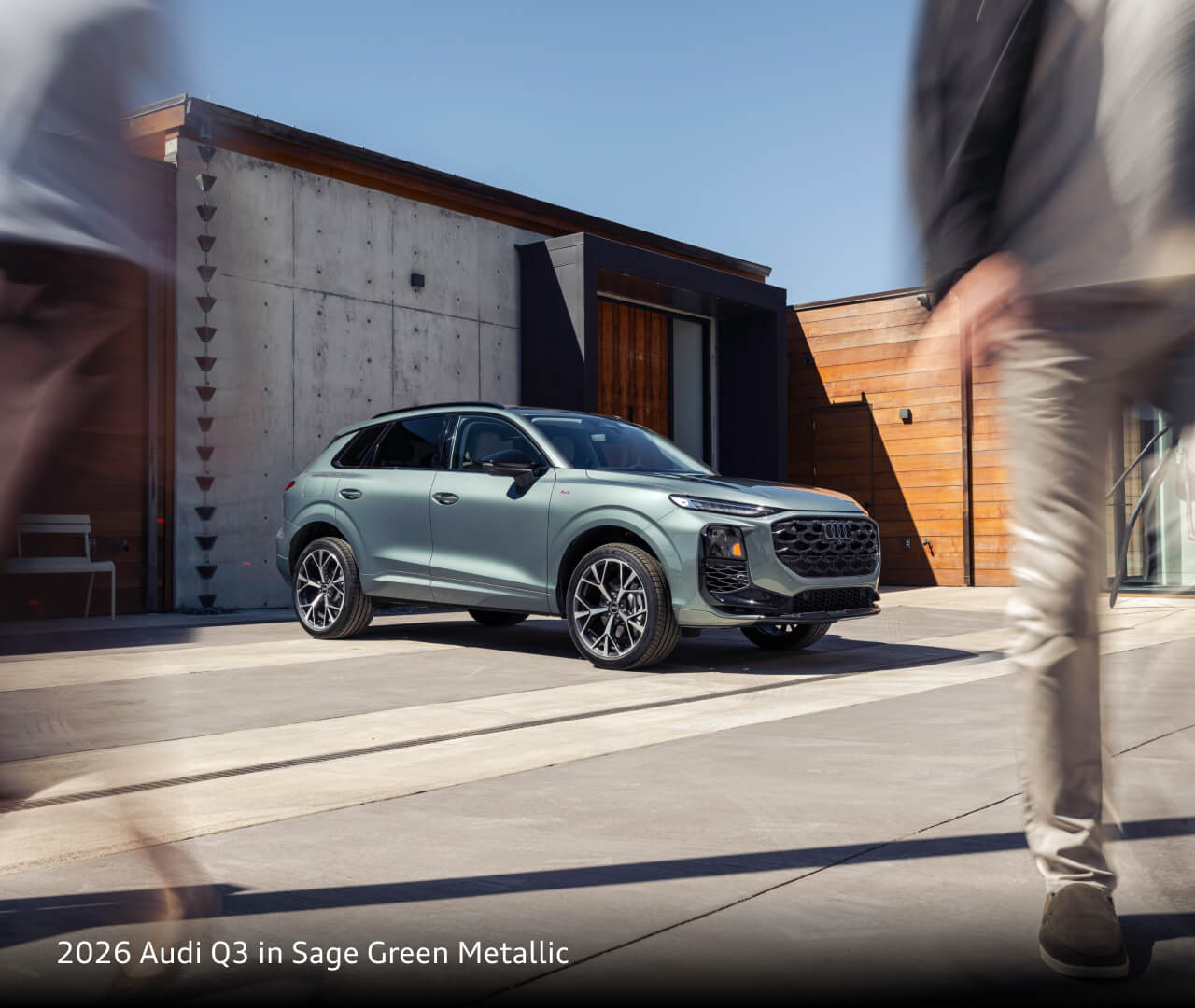 2026 Audi Q3 in Sage Green Metallic parked outside of a cement building