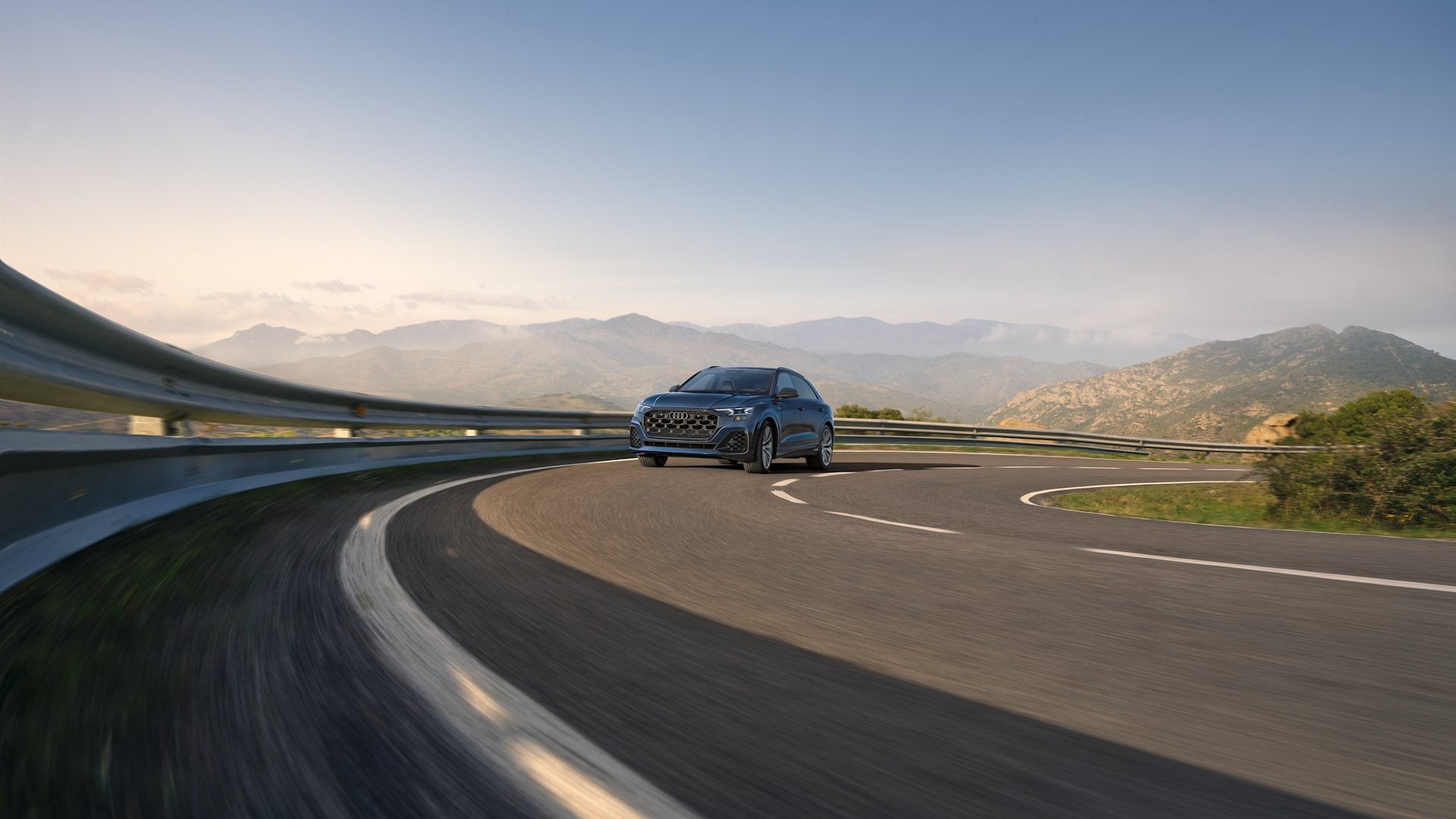 Audi Q8 driving on a curving highway.
