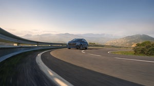 Audi Q8 driving on a curving coastal highway.