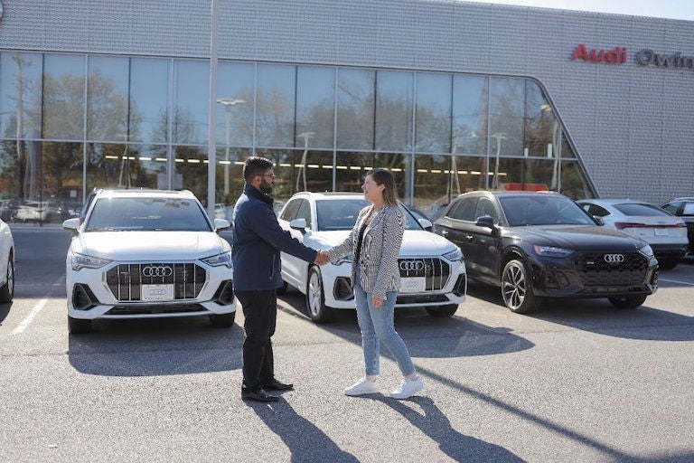Salesman greets customer outside of Audi dealership