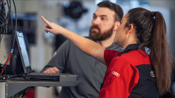 Two Audi techs looking at a vehicle for inspection. 