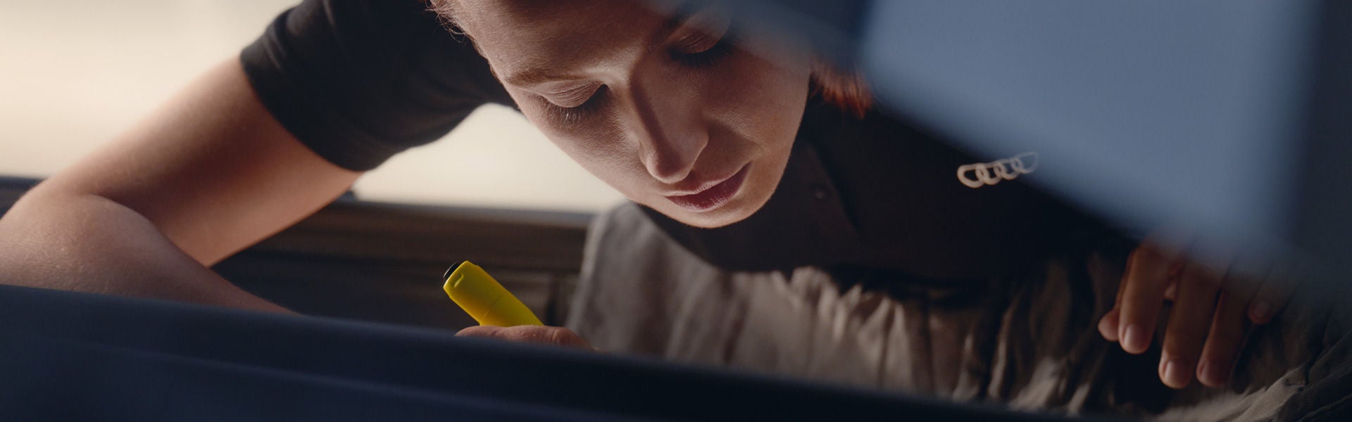 An Audi technician inspecting under the hood of an Audi vehicle.