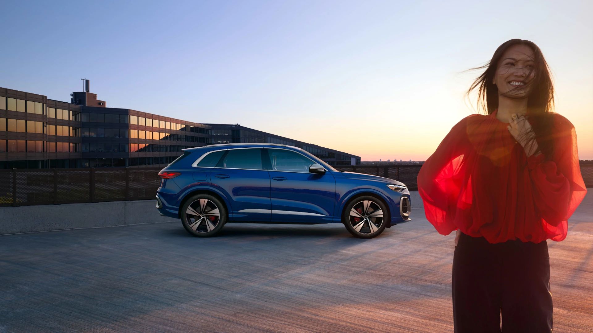 Woman smiling with an Audi SUV parked in the background.,
