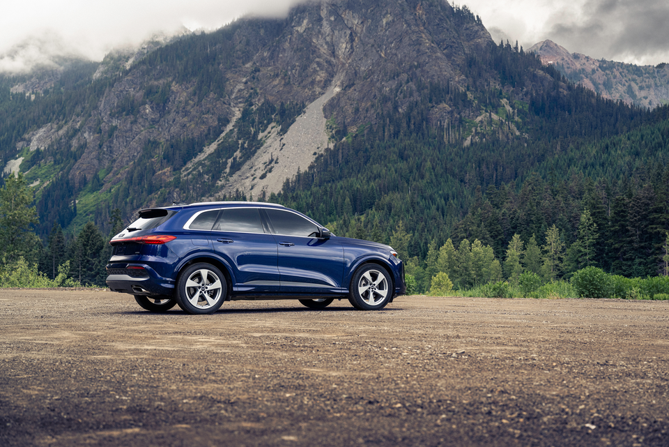 Dark blue Audi Q5 vehicle on a dirt road with a mountain at the background of the image. 