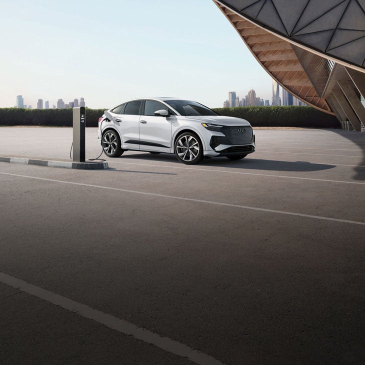 Three-quarter side-view of the Audi Q4 e-tron parked and charging. 