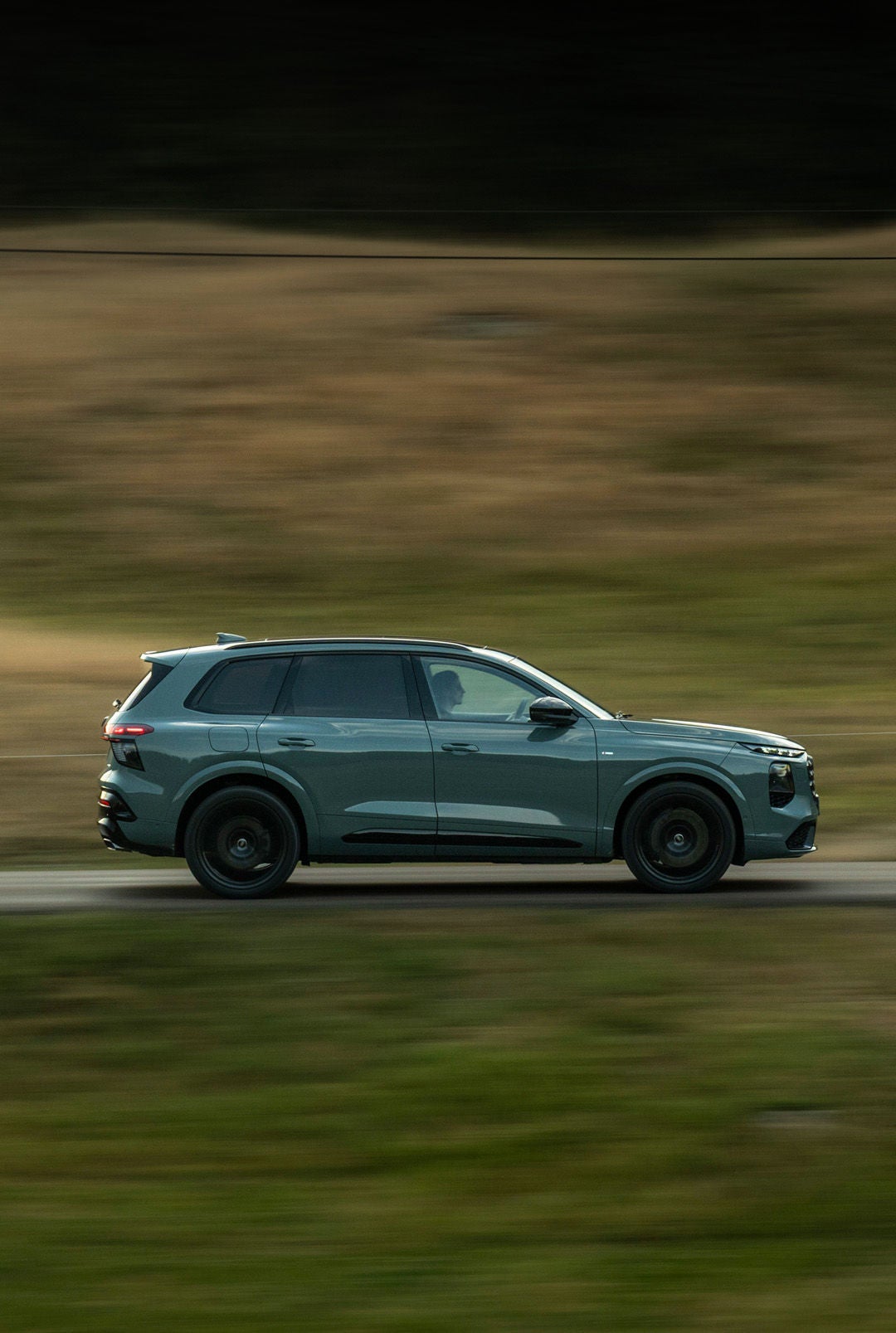Le nouveau Audi Q7 vu de profil roulant sur un chemin de campagne.