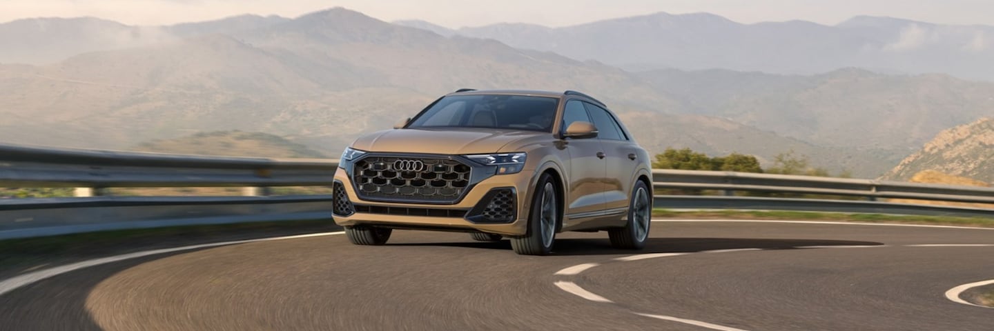 Side view of a beige Audi Q8 driving.