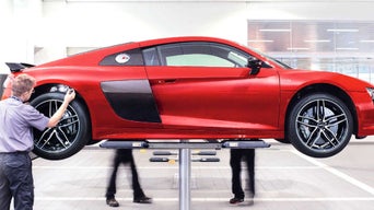 Service technicians conducting a multi-point inspection on an Audi vehicle.