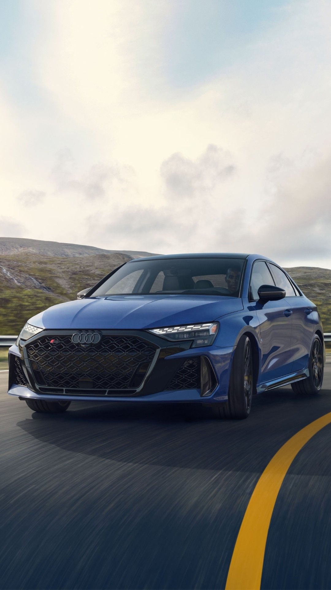 Three quarter front view of the Audi RS 3 driving on a slight curve on the highway.
