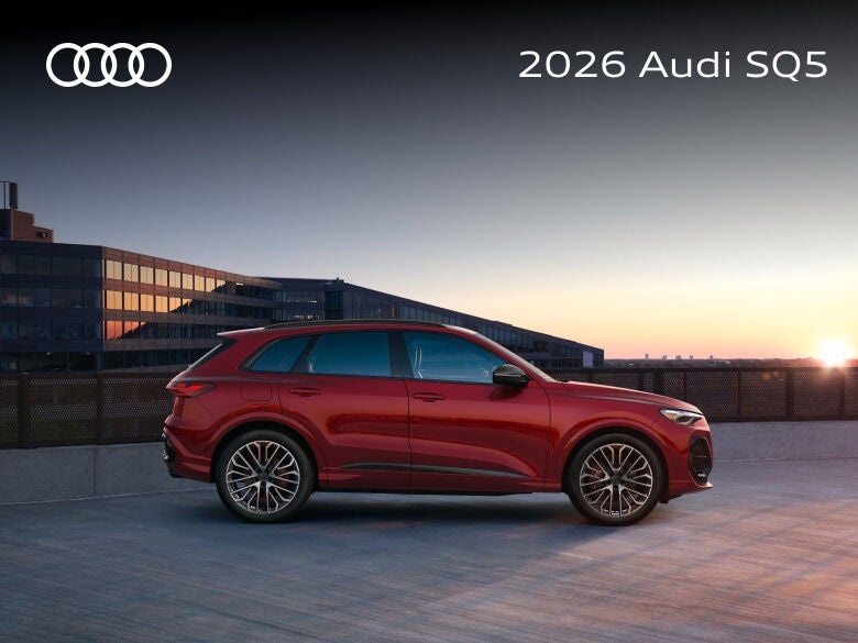 Profile view of a red 2026 Audi SQ5 parked on a rooftop lot at sunset.