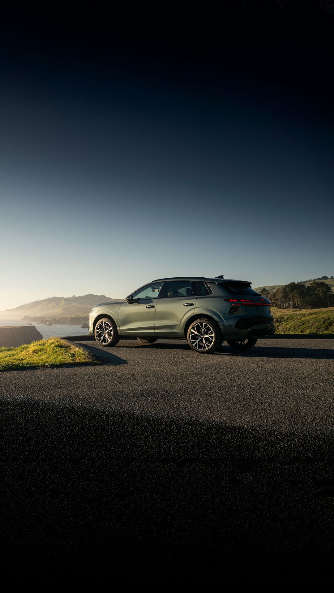 Side view of the Audi Q3 parked, overlooking a waterfront during sunrise.
