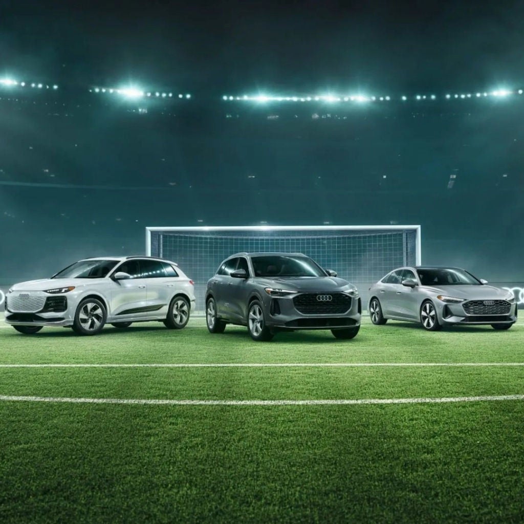 Three Audi vehicles parked on a soccer field.