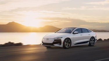 Side view of the Audi A6 Sportback e-tron accelerating next to a body of water.