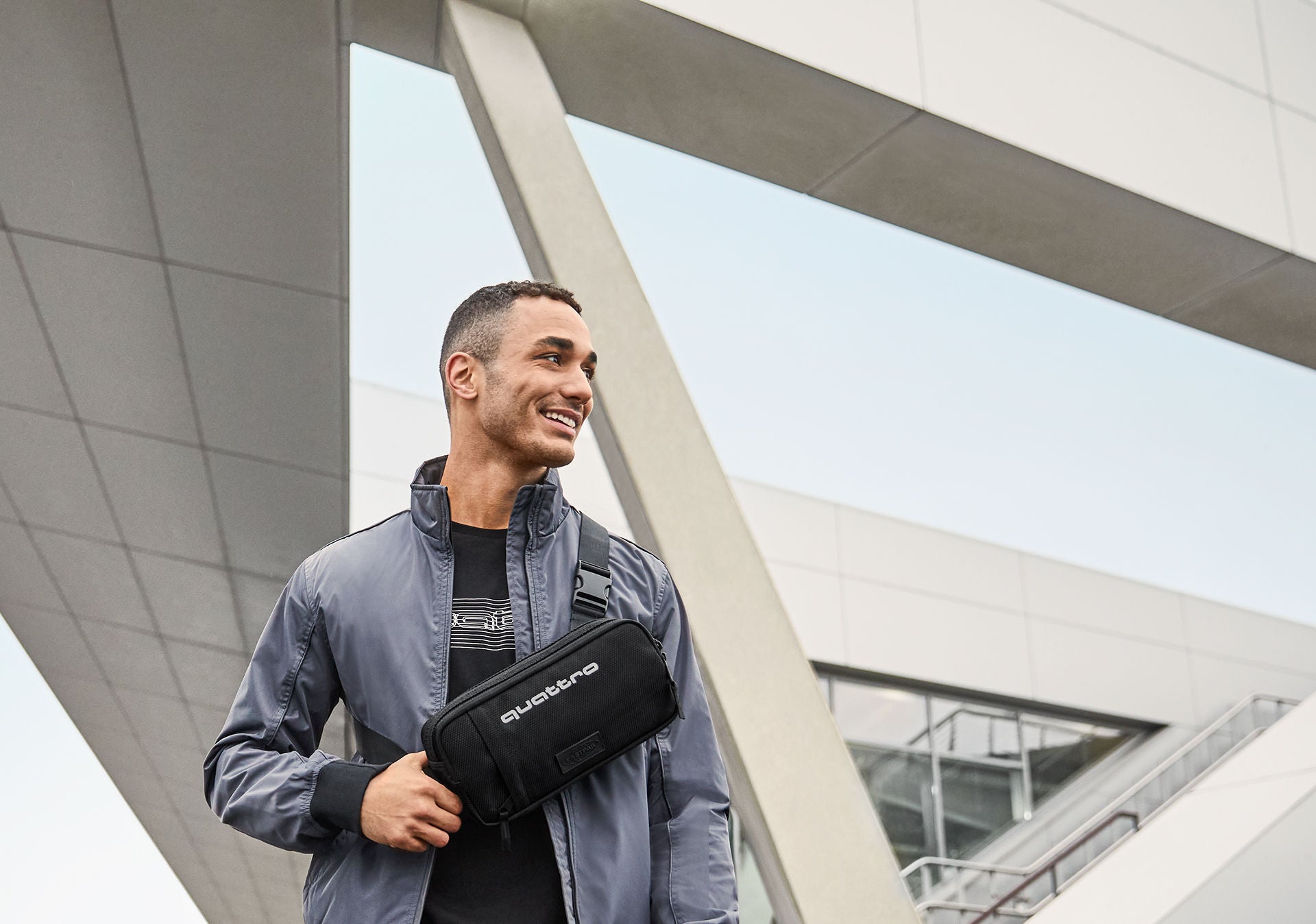 A man smiling in front of a modern building.