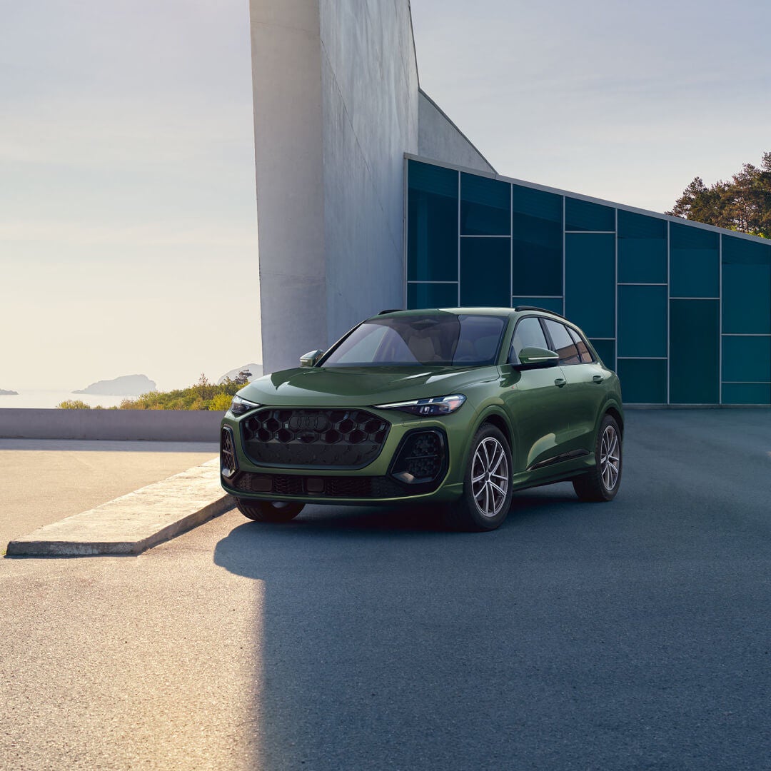 Front three-quarter view of a green Audi Q5 parked outside a modern building.