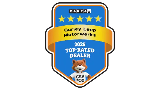 Audi sales specialist walking with a customer through the showroom. The sales specialist is handing the customer a key fob for an Audi vehicle. 