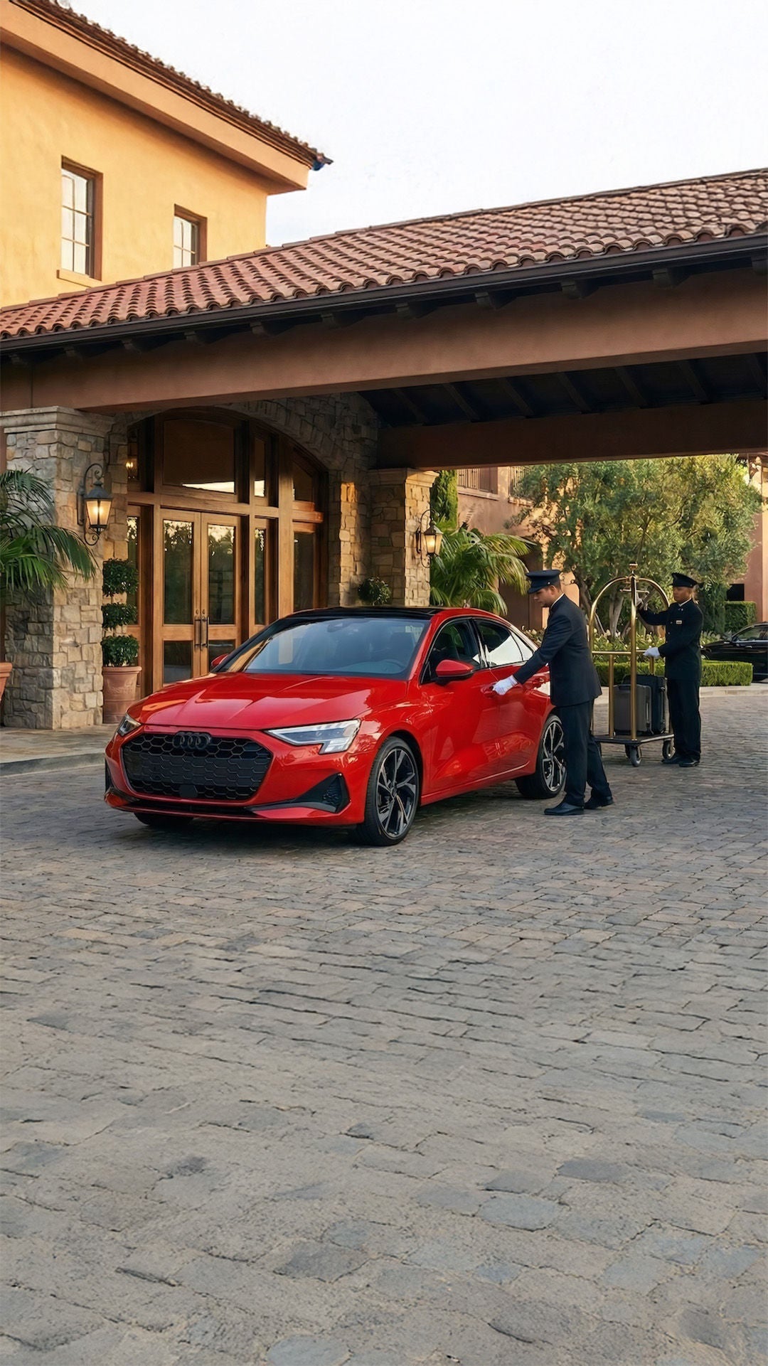 A red 2026 Audi A3 parked infront of a resort with valet opening the door