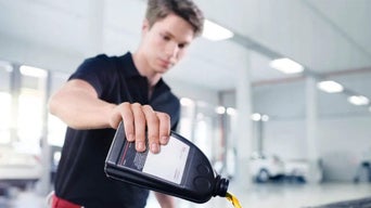 Service technician changing the oil in an Audi vehicle.