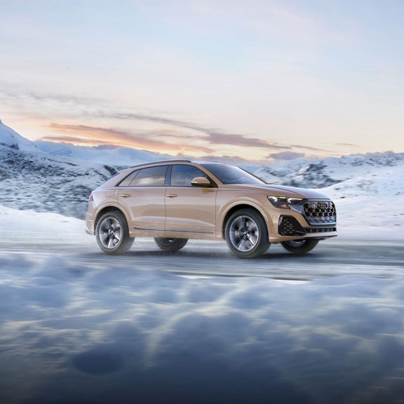 Side view of the Audi Q8 accelerating in a wintery landscape.