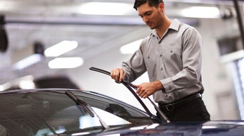 Service technician replacing wiper blade refills on Audi vehicle.