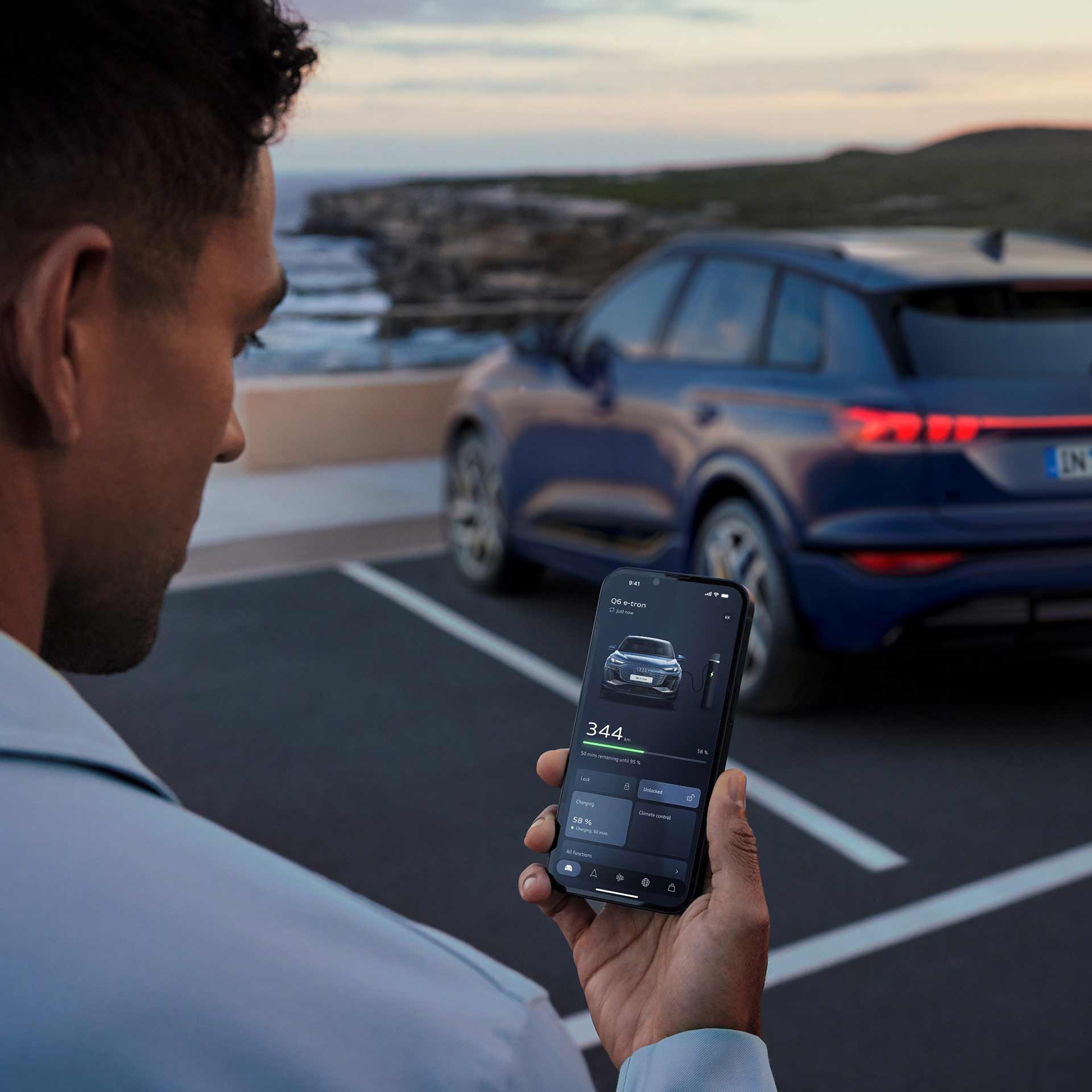 A woman checking the charging status of her Q8 e-tron vehicle as it's plugged in next to her.