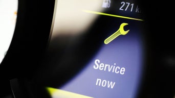 Close-up of a car dashboard flashing a "Service now" alert.
