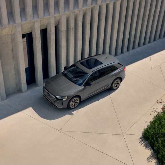 Aerial view of a gray Audi Q8 e-tron parked next to a building. 