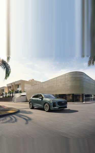 2026 Audi Q3 driving past modern architecture