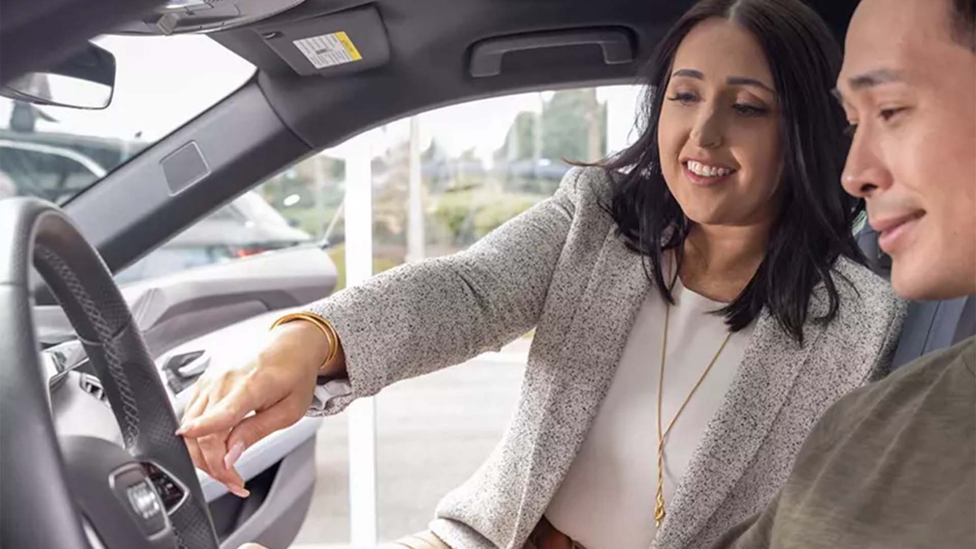 Employé Audi montrant l’intérieur d’un véhicule Audi à un client.