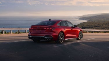 Three-quarter rear view of the Audi S5 accelerating on an oceanside road.